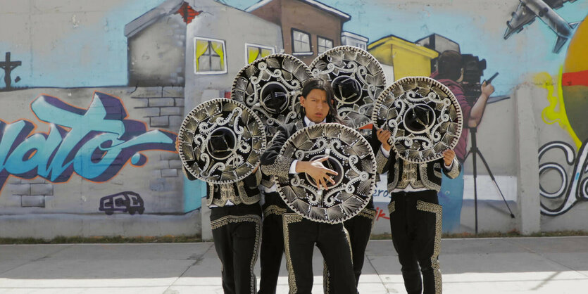 Menschen mit Sombreros vor einer Wand mit bunten Graffitis