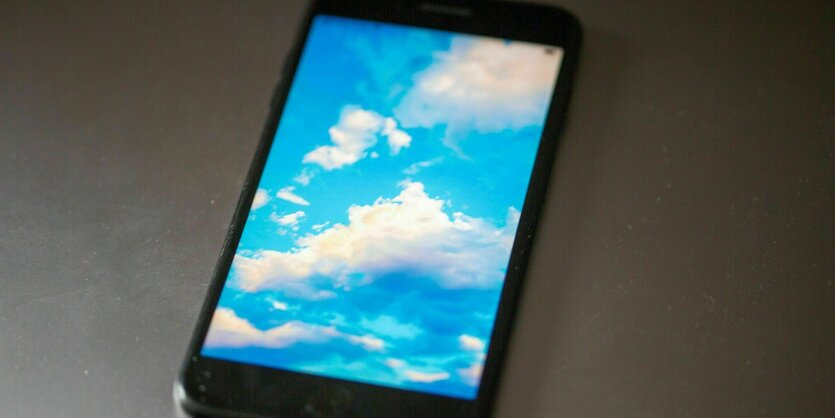 Das Display eines Smartphones mit blauem Wolkenhimmel