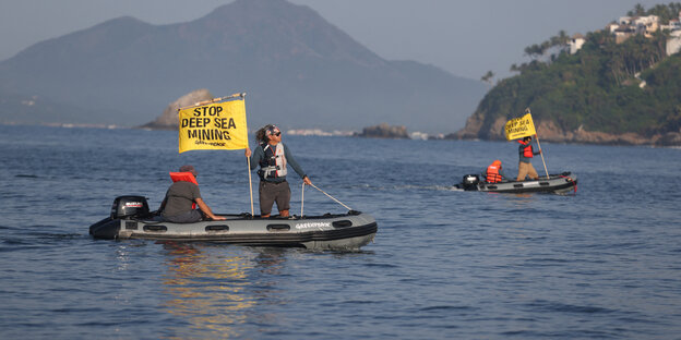 Zwei Aktivisten in einem Schlauchboot audf dem Wasser. Einer hält ein Schild mit der Message: Stopp Deep Sea Minning