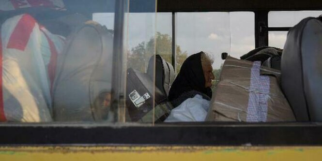 Eine ältere Frau sitzt einem Bus, der Flüchtende aus Bergkarabach nach Armenien bringt