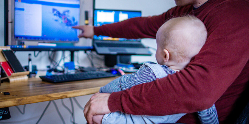 Mensch am Computer mit kleinem Kind auf dem Schoß