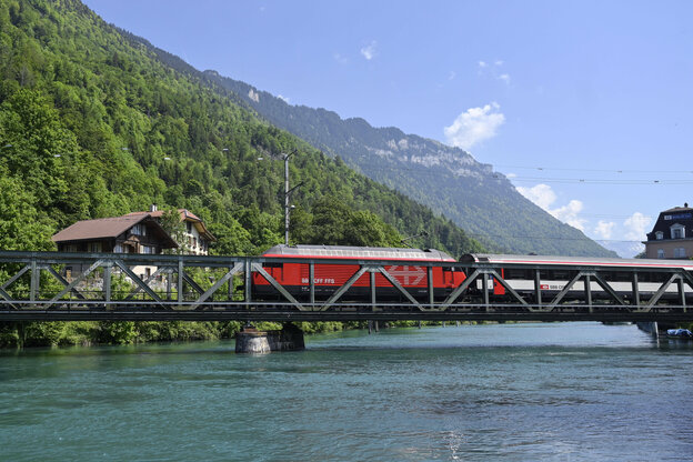 Ein Zug auf einer Brücke vor Bergen.