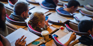 Eine Studentin inmitten von Studenten im Hörsaal