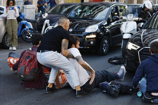 ein Autofahrer versucht einen Aktivisten, der die Fahrbahn blockiert, von der Straße zu zerren
