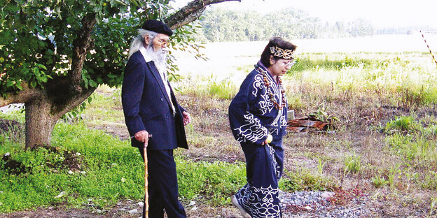 Eine Frau in einem traditionelle Kostüm und ein alter Mann mit langem Bart auf einem Spaziergang