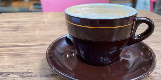 Eine Tasse Cappuccino steht auf einem Holzstisch