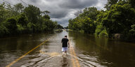 Eine Person läuft eine überflutete Straße entlang