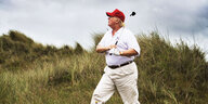 Donald Trump mit Golfschläger in einer Dünenlandschaft
