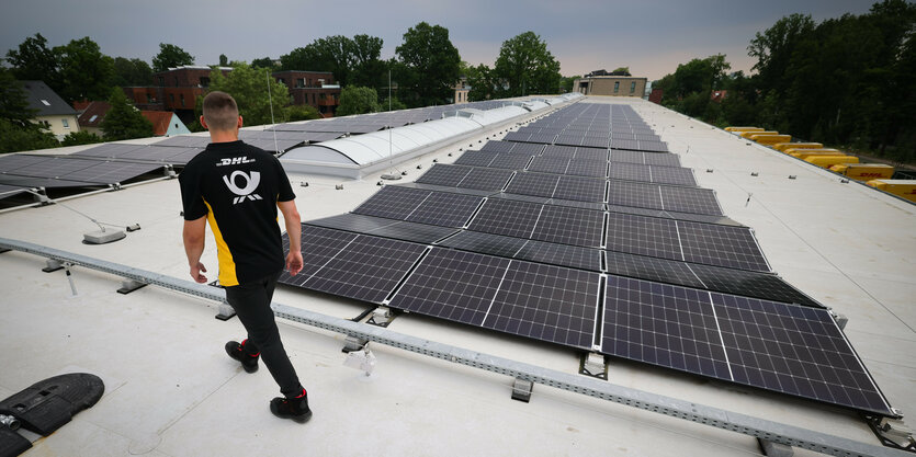 Arbeiter auf einem Hallendach mit PV-Anlage