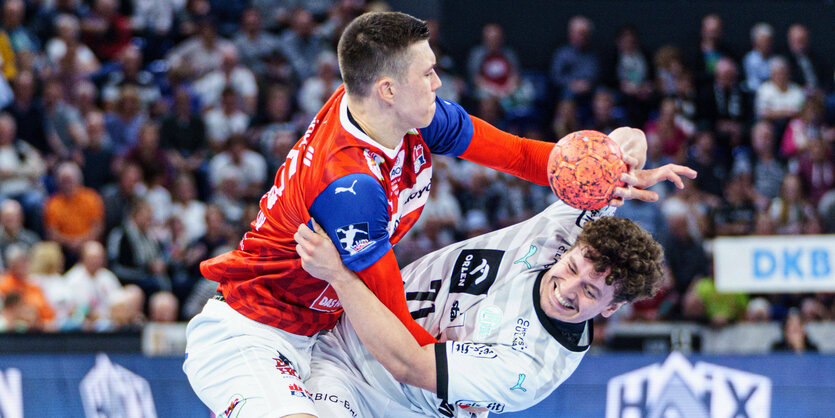 ein Handballspieler mit Ball drängt sich an einem anderen vorbei