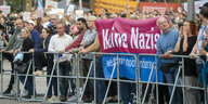 Kundgebung, Menschen stehen vor Absperrgittern, in der Mitte ein Transparent: Keine Nazis