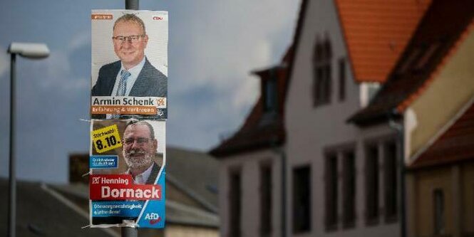 Zwei Wahlplakate an einem Laternenpfahl