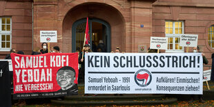 Zwei Banner werden hochgehalten, auf dem einen steht "Samuel Kofi Yeboah Nie Vergessen" auf dem anderen "Kein Schlussstrich!", unter dem letzteren die Antifa-Flagge