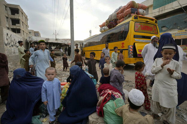 Afghanische Familien warten mit ihren Kindern am 6. Oktober in Karatschi auf die Abfahrt ihres gelben Busses nach Afghanistan