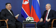 Kim Jong Un und Putin vor Flaggen.
