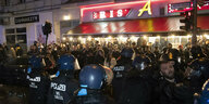 Behelmte Polizisten vor einer Menschenmenge.