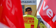 Streikende stehen mit Fahnen von Verdi vor einem Verteilzentrum des Online-Händlers Amazon