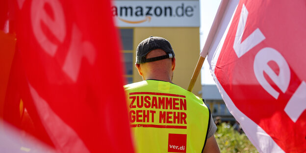 Streikende stehen mit Fahnen von Verdi vor einem Verteilzentrum des Online-Händlers Amazon