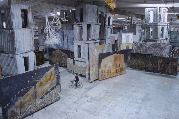 Der Künstler Anselm Kiefer ist mit dem Fahrrad zu sehen, zwischen haushohen Skulpturen