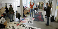 junge Menschen stehen auf einem Flur, am Boden liegen gemalte Transparente