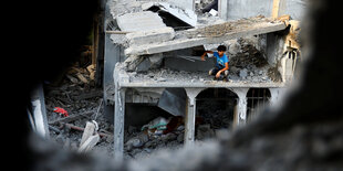 Ein palästinensischer Junge sitzt nach israelischen Angriffen im südlichen Gazastreifen am 11. Oktober auf einem beschädigten Haus, das durch die Trümmer zu sehen ist.