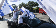 Mehrere Personenn in einem Auto mit Israel-Flaggen.