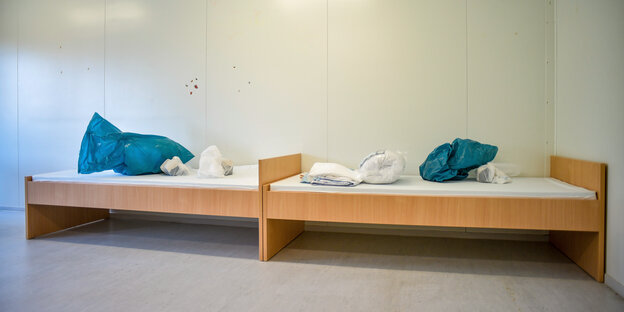 Zwei leere Betten mit Müllsack und Bettwäsche in einer Notunterkunft in Berlin