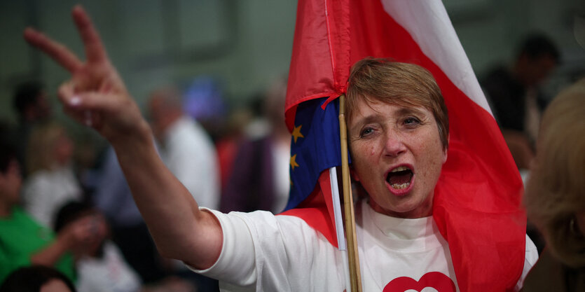 Eine Person macht ein Victory-Zeichen bei einer Demonstration.