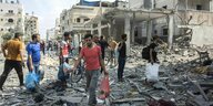 Menschen in Gaza-Stadt stehen mit Tüten in der Hand auf Trümmerhaufen