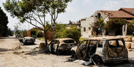 Verbrannte Fahrzeuge und zerstörte Häuser nach einem Angriff.