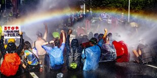 Personen bei einer Straßenblockade werden von einem Wasserwerfer besprüht.