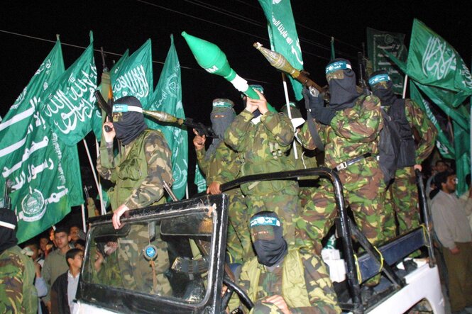 Vermummte Kämpfer mit Waffen auf einem Jeep.