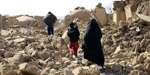 Nach dem Erdbeben in Afghanistan geht eine Familie über Trümmer