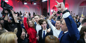 Menschen feiern ausgelassen in einem rot-weiß beleuchteten Saal