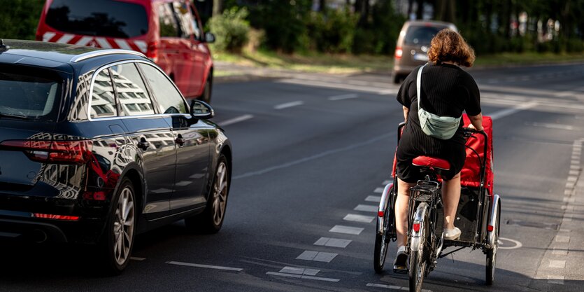 Eine Frau unterwegs mit einem Lastenfahrrad auf einem städtischen Radweg