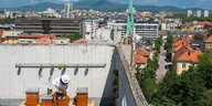 Ein slowenischer Imker auf dem Dach, im Hintergrund eine Stadt.