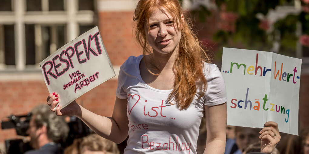 Eine junge Frau hält ein Schild mit der Aufschrift «Respekt vor sozialer Arbeit» beim Besuch von Kanzlerin Merkel am EU-Projekttag im Oberstufenzentrum für Sozialwesen Jane-Addams-Schule im Stadtteil Berlin-Friedrichshain. Bild von 2018.