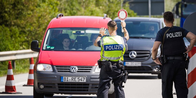 Polizisten halten an der Grenze ein Auto an