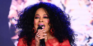 Porträt von Diana Ross, mit Mikrofon in der Hand, sie singt, die Haare offen in rotem Kleid