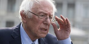 Bernie Sanders, graue Haare, Brille, Anzug, rückt seine Brill zurecht