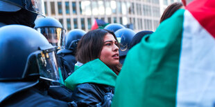 Polizist:innen und Demonstrat:innen bei einer Kundgebung mit Flaggen.