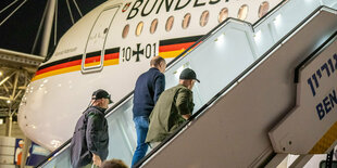 Israel, Tel Aviv: Bodyguards bringen Bundeskanzler Olaf Scholz (SPD, M) nach einem Luftalarm am Ende seines Solidaritätsbesuches in Israel in sein Flugzeug.