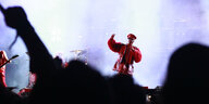 Till Lindemann in roter Lederkleidung auf der Bühne, Fans recken die Arme