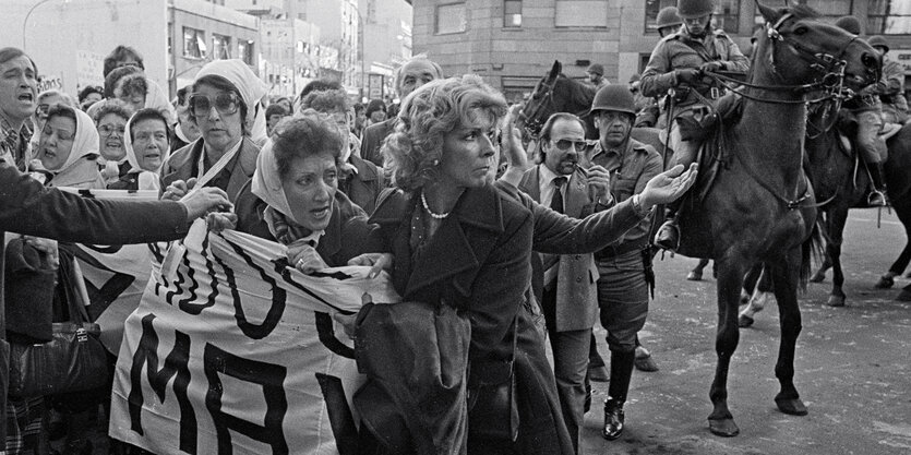 Frauen mit Transparenten bei einer Demonstration, im Hintergrund berittene Polizei