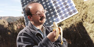 Amory Lovins schaut auf eine geöffnete Banane, im Hintergrund stehen Solarzellen auf einem Ständer