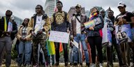 Aktivisten protestieren mit Regenbogenfahne und Plakaten