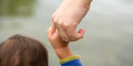 Ein*e Erwachsene*r hält die Hand eines kleinen Kindes.