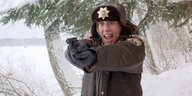Eine Polizistin in einer Schneelandschaft zielt mit ihrer Pistole in Richtung Kamera