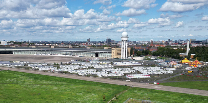 Das Bild zeigt Wohncontainer am Rande des Tempelhofer Felds vor dem Flugfahefngebäude.