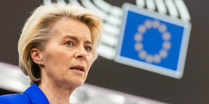EU-Kommissionspräsidentin von der Leyen, im Hintergrund das Logo des EU-Parlaments